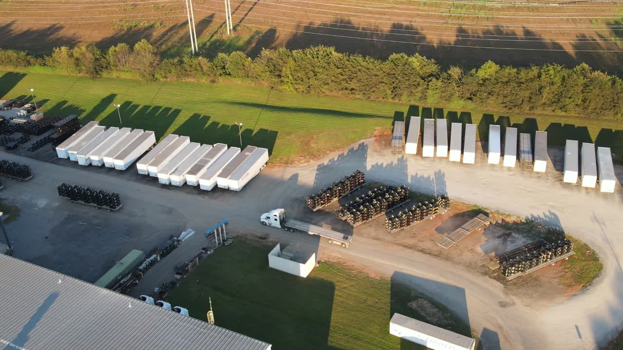camión semiplano vacío conduciendo en el patio del almacén hasta el área de carga - disparo de un dron de seguimiento aéreo durante la tarde soleada