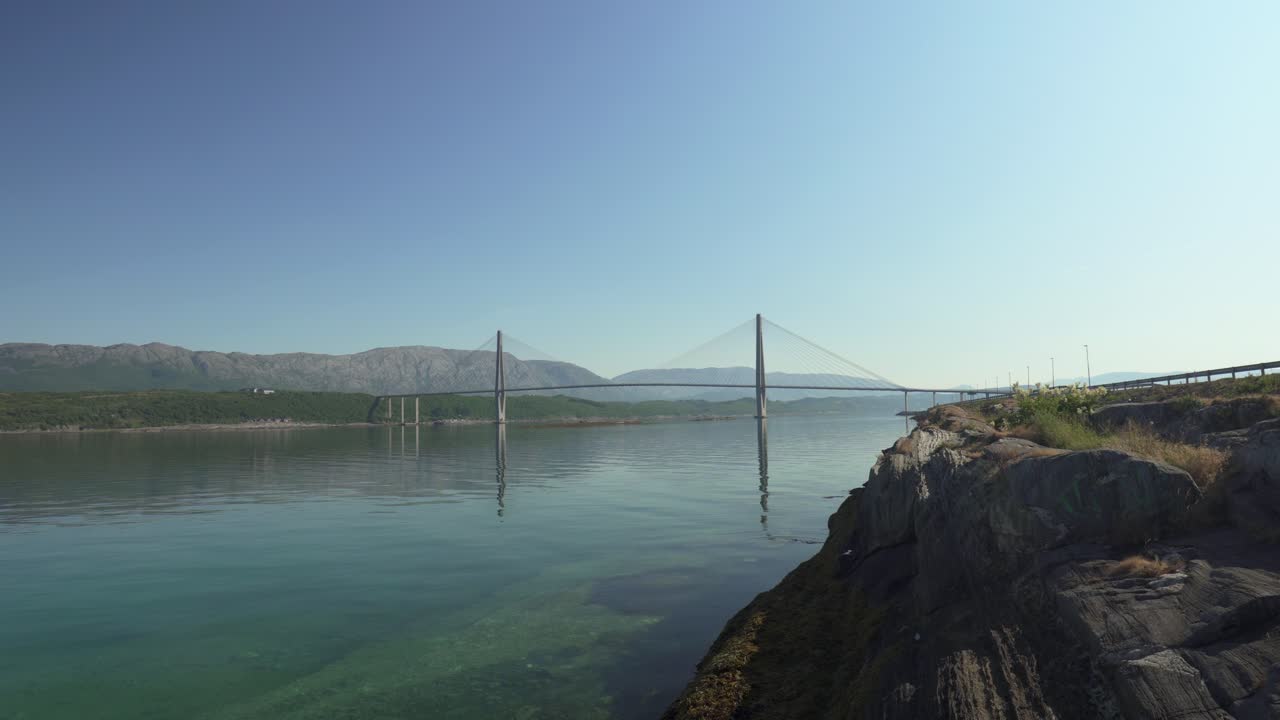 Helgelandsbrua, Noruega: uma elegante ponte suspensa que se estende sobre águas costeiras calmas sob um céu azul claro – Close estático