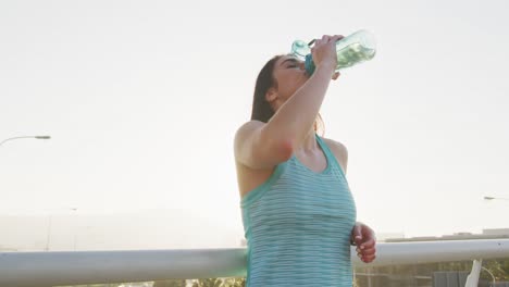 young runner drinking water after running