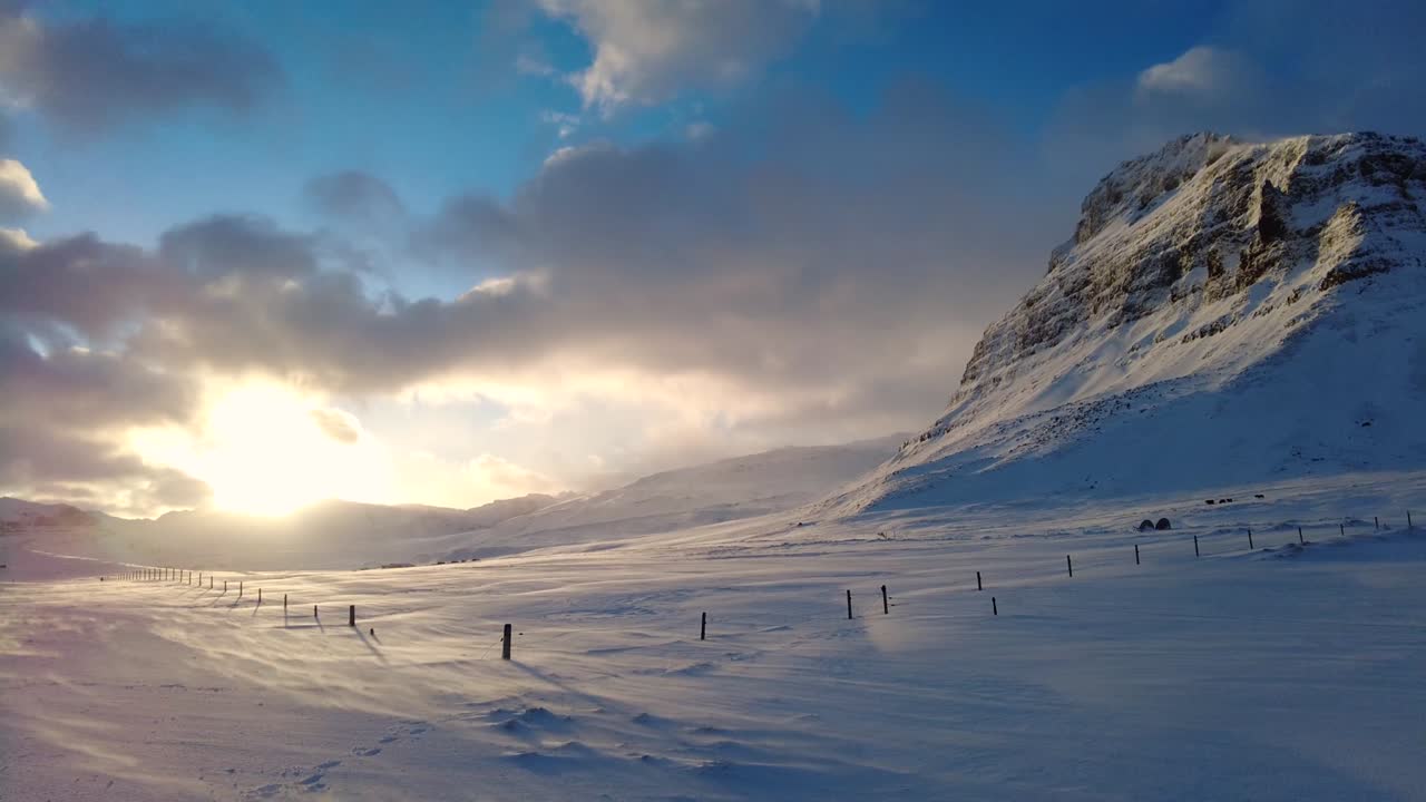 широкий кадр автомобиля, едущего по исландской дороге со снежно-белыми горами и заходом солнца в сельской местности, зимнее время.