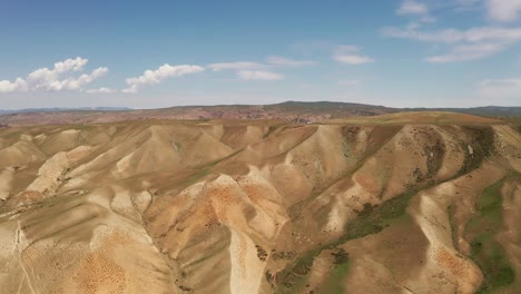 rolling mountains under blue sky and white clouds.