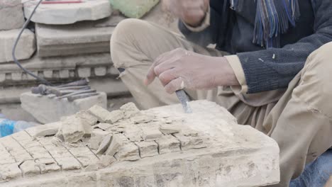 An-old-man-carving-the-relics-of-the-temple-stone-for-reconstruction-of-the-temple-which-was-destroyed-by-the-earthquake-in-Bhaktapur-Durbar-Square,-Nepal