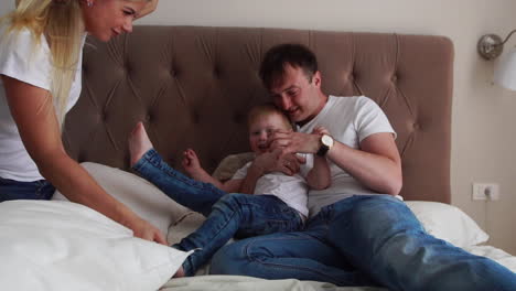 familia feliz jugando con almohadas peleando en la cama en casa