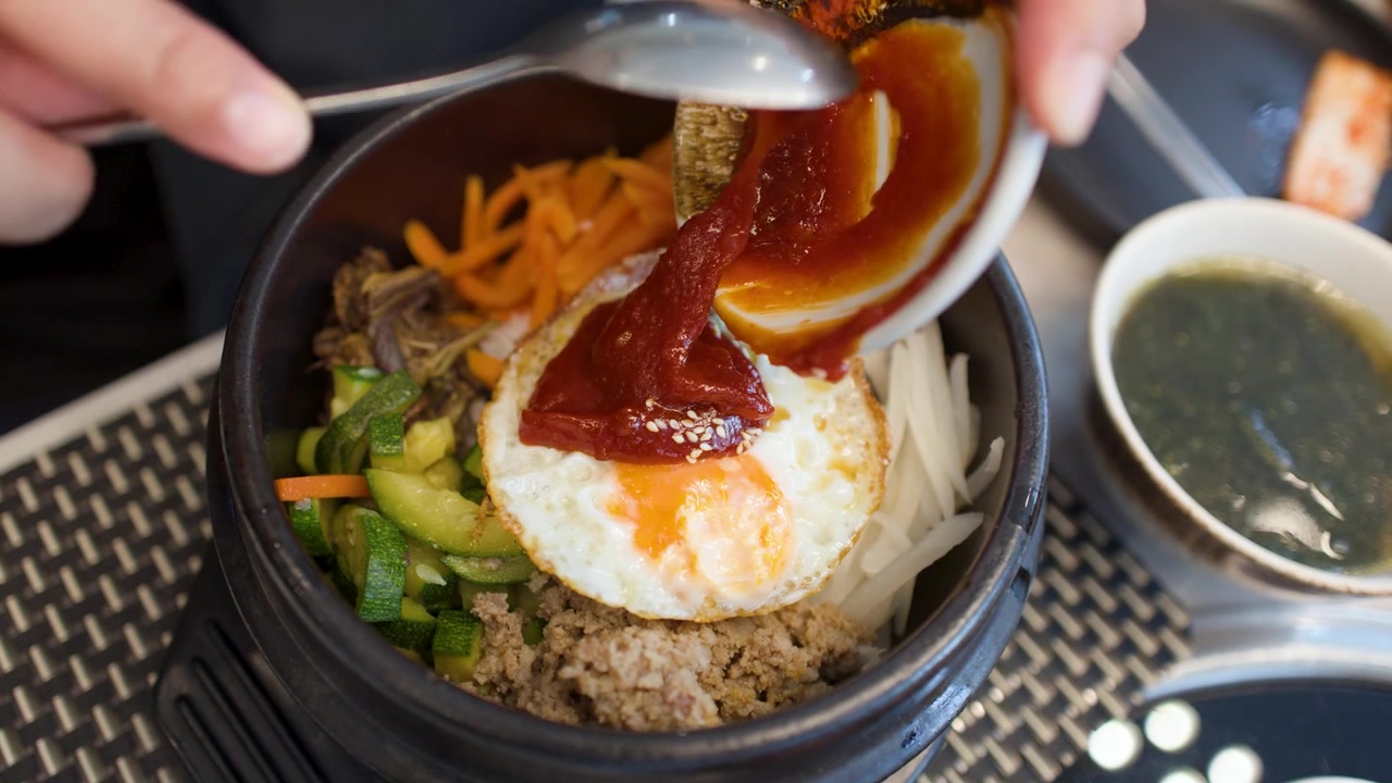 Foto dari atas pasta cabai merah yang disendokkan ke atas telur goreng dalam bibimbap.