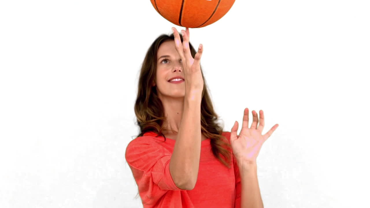 mujer divirtiéndose con una pelota de baloncesto en fondo blanco