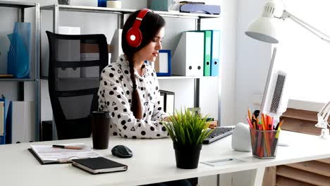 businesswoman in red headphones using laptop in modern office