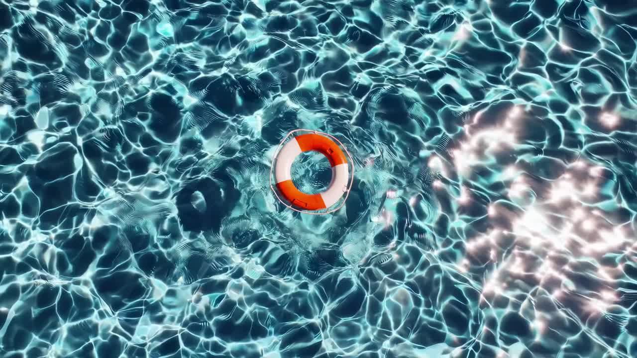 Top-down video shot of a vibrant pool with rippling water, centered on a bright orange lifebuoy
