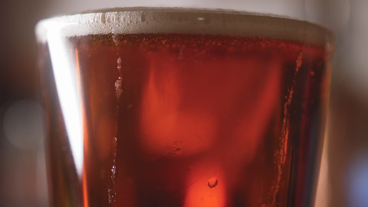 Primo piano di birra versata in un bicchiere da pinta con bolle vorticose che salgono al suo interno 4K