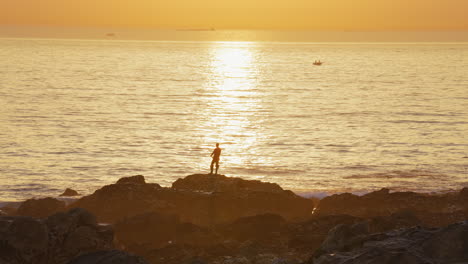 silueta de un pescador pescando en el océano durante el amanecer