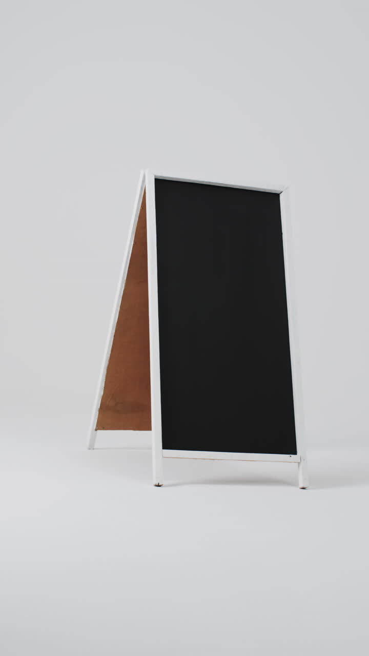 Vertical video of blackboard sign on white stand with copy space on white background