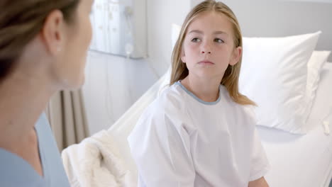 Caucasian-female-doctor-talking-with-girl-patient-sitting-on-hospital-bed,-slow-motion