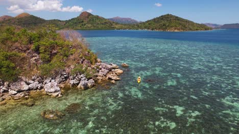 4k drone video of a couple kayaking around cyc while on a boat trip from coron in palawan, philippines. the water here looks crystal clear and you can see the coral reefs beneath the surface.