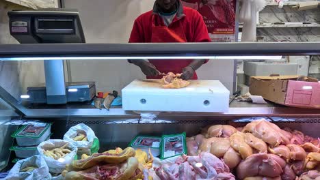 butcher chopping chicken at a market stall