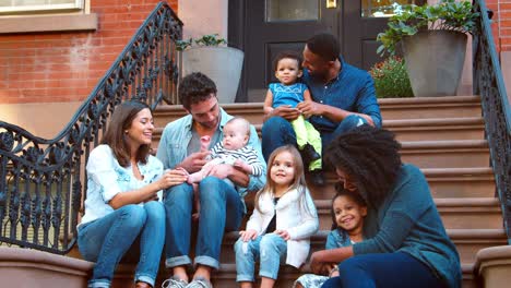 two families with kids sitting on front stoop in brooklyn