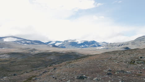 Beautiful-max-view-drone-shot-of-a-stony,-barren-landscape-with-isolated-meadows-and-mountains-on-the-horizon,-sunny-day,-no-people,-outdoor,-wilderness