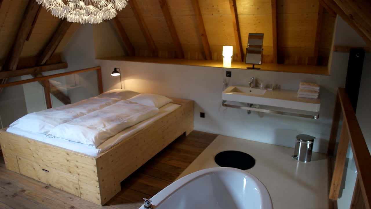 유리 장벽으로 둘러싸인 소박한 다락방 침실의 아늑한 침대