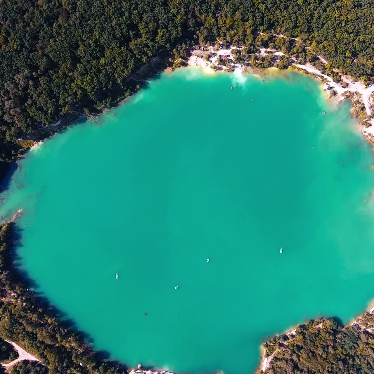 Turquoise spot of the lake in the forest. Wonderful picturesque view over the pond with white sandy banks around. Top view