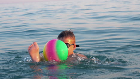 child playing with ball when bathing in the sea on vacation