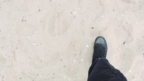 a person walking on sand with black shoes and cargo pants during summer time in slow motion