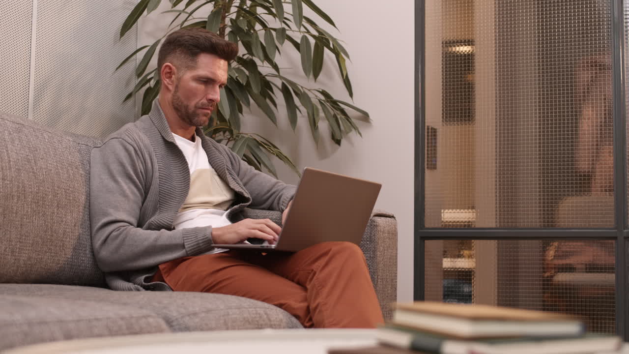 hombre usando computadora portátil en el sofá