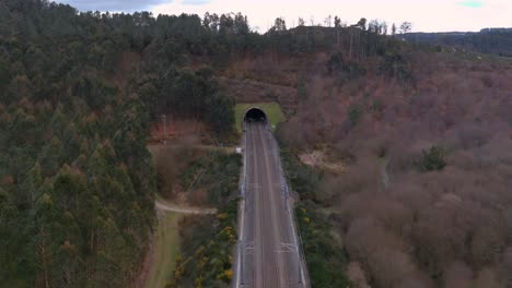 aerial dolly back from railway tunnel entrance in rural landscape