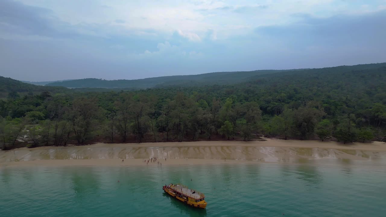 Tourists enjoying Koh Rong Sanloem beach and sea, swimming near a tour boat, aerial view from above. Great aerial view flight overflight flyover drone