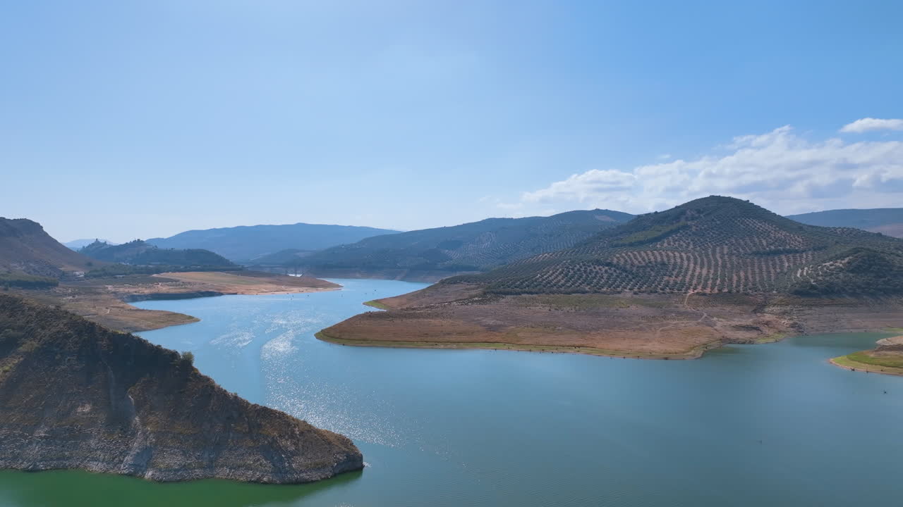 코르도바 지방의 주요 물 공급처인 이즈나하르 저수지를 둘러싼 거대한 올리브 숲으로 인 언덕 위로 날아갑니다.
