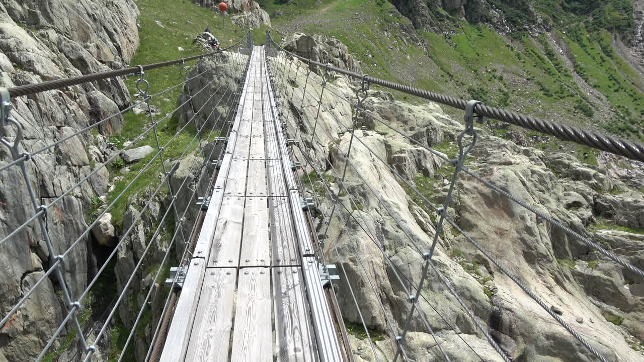 Vista in movimento lungo la passerella del ponte sospeso di Trift sopra una gola alpina rocciosa vicino a Gadmen, Oberland Bernese, Svizzera, concetto di viaggio avventura