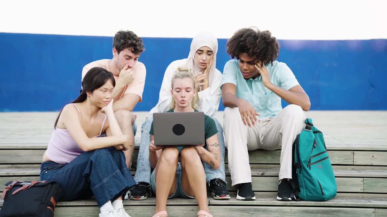 Gruppo di studenti eterogenei che collaborano su un portatile all'aperto