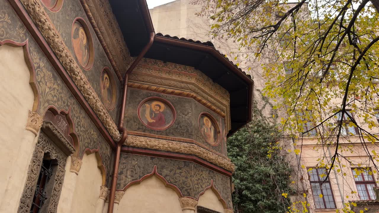 ornate painted walls and carved details of Stavropoleos Monastery beside ivy and trees