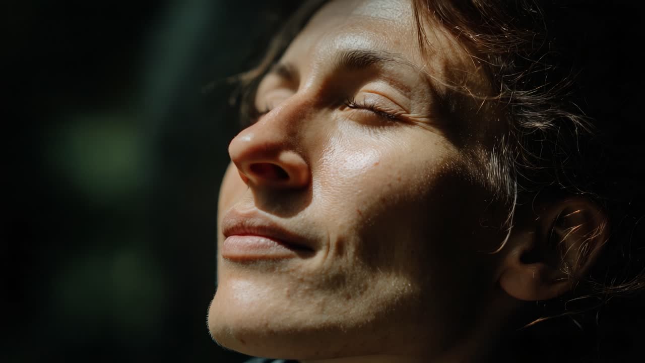 A Serene Moment of Reflection: A Woman Enjoys the Peaceful Warmth of Sunlight on Her Face, Finding Tranquility in Nature's Embrace