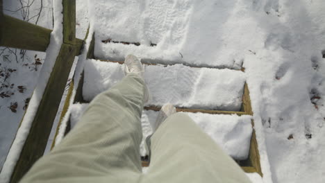 overhead view of feet walking down snow-covered wooden steps