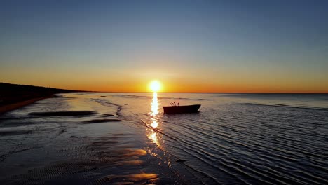 Una-Puesta-De-Sol-Inusualmente-Hermosa-En-El-Océano-Revela-La-Belleza-Del-Terreno-Arenoso-De-La-Playa-Y-En-La-Distancia-Hay-Un-Barco-De-Pescadores-Lleno-De-Aparejos-De-Pesca.