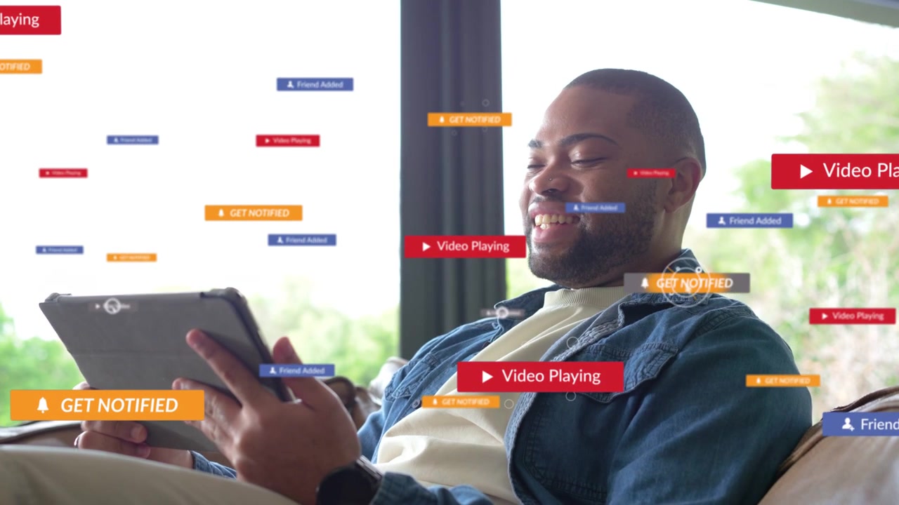 Adult man holding tablet on couch, badges appearing and inviting tapping for marketing engagement