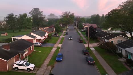 car driving through quaint american neighborhood during foggy morning sunrise