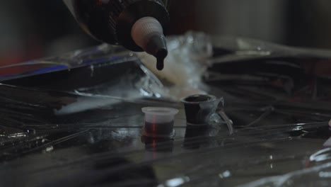 a tattoo artist puts drops of ink into a small container to load the iron or tattoo pen to avoid contamination