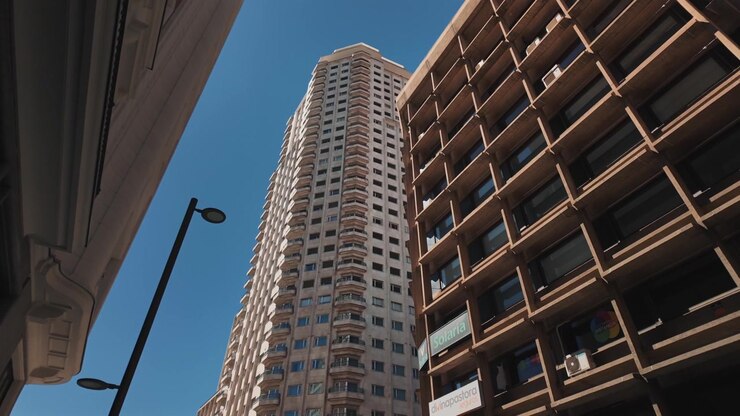 Vista em ângulo baixo de uma torre residencial alta emoldurada por edifícios circundantes no centro de Madrid