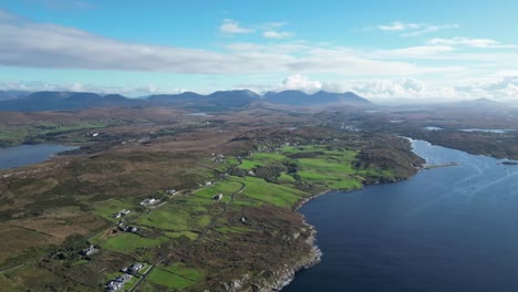 rural landscape with lake, fields and mountains in municipal district of conamara, republic of ireland - drone shot