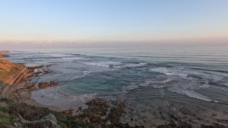 waves crashing against rocky shore at sunset