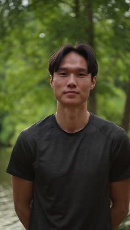 Vertical-Video-Portrait-Of-Smiling-Mid-Adult-Man-Exercising-Doing-Work-Out-Outdoors-In-Forest-Wearing-Sports-Clothing-Shot-In-Real-Time