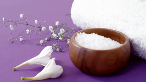 sea salt in wooden bowl, towel and flowers