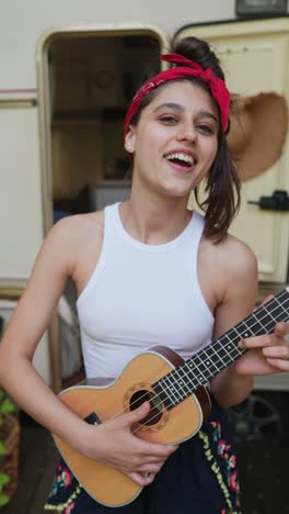 young woman playing ukulele in campervan