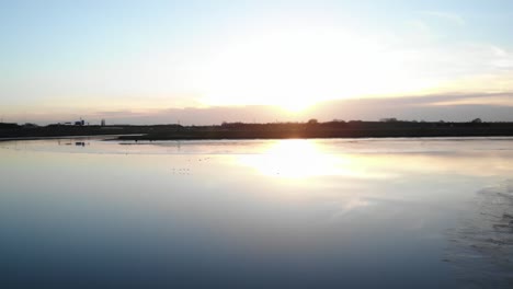 Puesta-De-Sol-Sobre-Un-Tranquilo-Lago-Reflexivo.-Toma-Amplia-Aerea