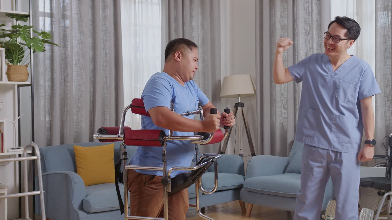 아시안 남성 간호사가 커를 사용하는 환자에게 손을 흔들며 집에서 물리 치료를 하는 동안 혼자 고 손을 들고 격려합니다.