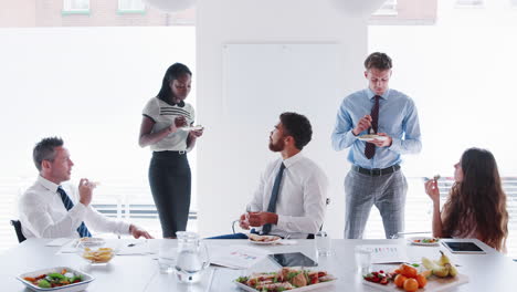 Hombres-Y-Mujeres-De-Negocios-Reunidos-En-Una-Moderna-Sala-De-Juntas-Durante-Un-Almuerzo-De-Trabajo-Filmado-En-Cámara-Lenta.