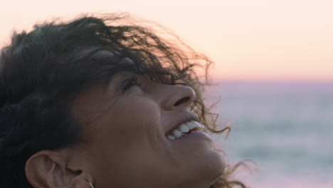 Retrato-De-Cerca-De-Una-Hermosa-Mujer-Hispana-Mirando-Hacia-Arriba-Explorando-La-Atención-Plena-Contemplando-La-Espiritualidad-Con-El-Viento-Soplando-El-Pelo-Disfrutando-De-La-Tranquila-Playa-Al-Atardecer