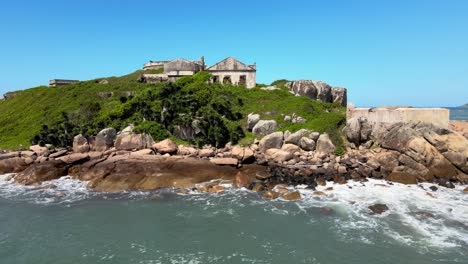orbital aerial drone scene of an ancient 18th century ruined fortress on a small isolated rocky island imperial defense system, florianópolis, santa catarina, brazil, araçatuba, naufragados beach