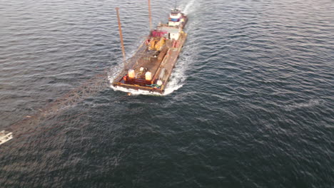 Aerial-Circle-Dolly-Around-Floating-Crane-Platform-Being-Pushed-By-Tug-Boat-Off-Coney-Island,-New-York