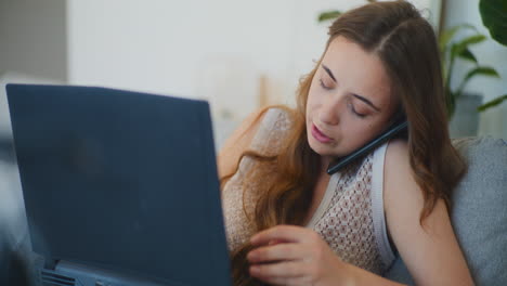 mujer ocupada escribiendo en el sofá de la computadora portátil