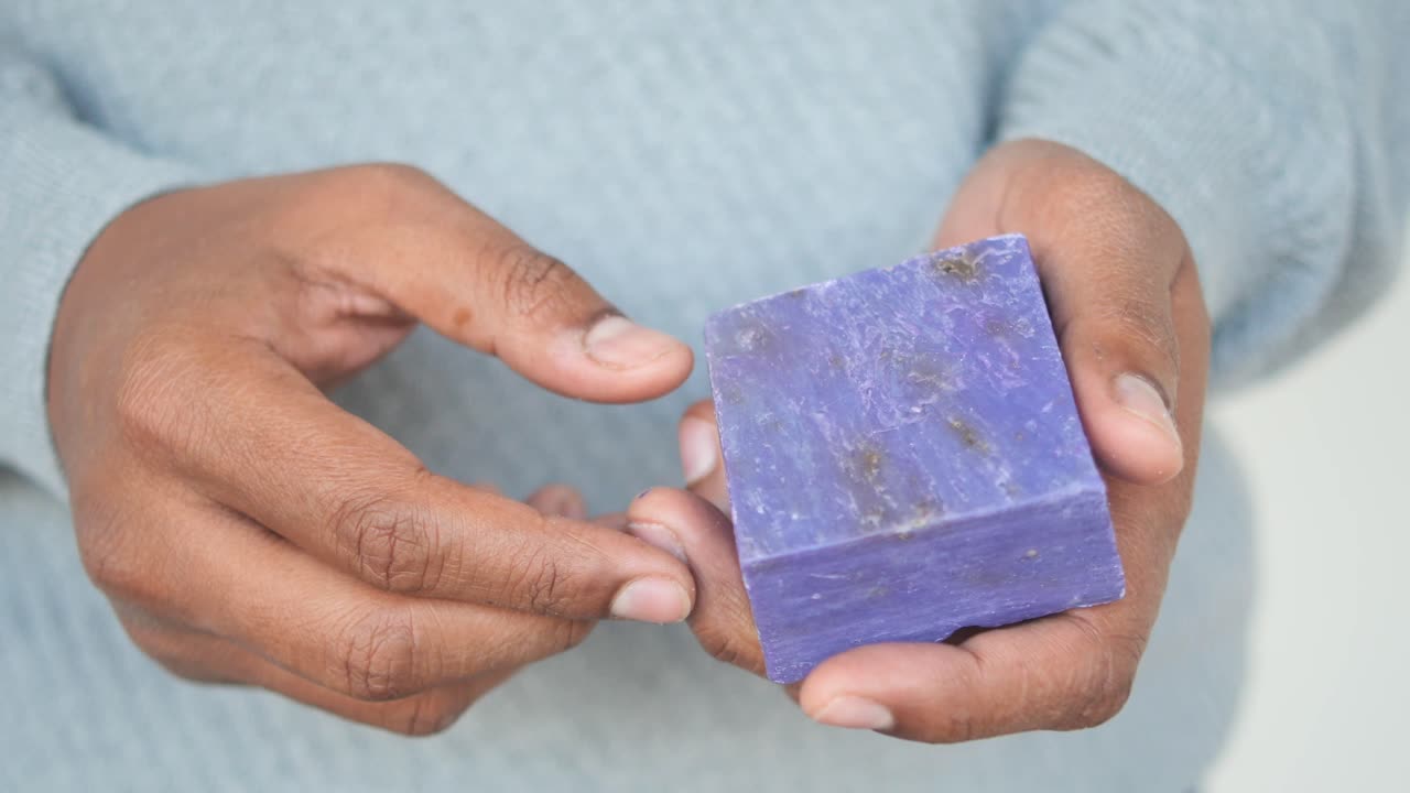 Person Holding a Piece of Purple Soap
